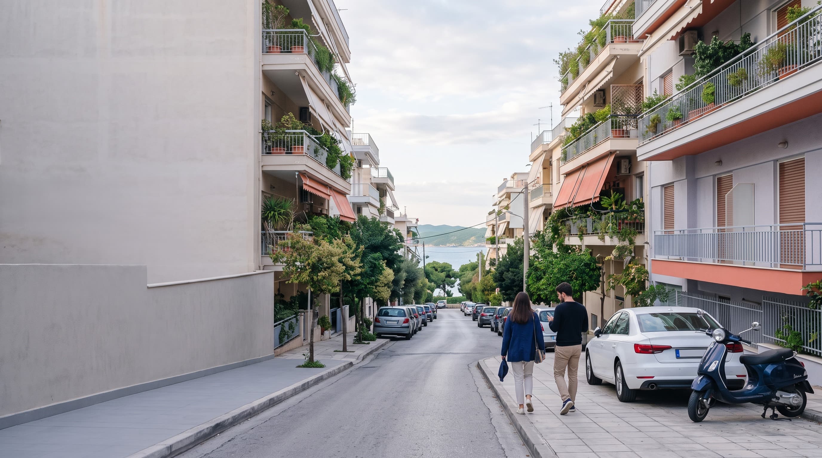 Ηλιόλουστος δρόμος γειτονιάς στην Αθήνα με παρκαρισμένο αυτοκίνητο και νεοκλασική είσοδο